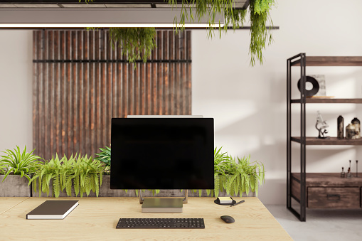 Large blank monitor with keyboard and office supplies on desk. Concrete floor and rustic wooden shelf. Render