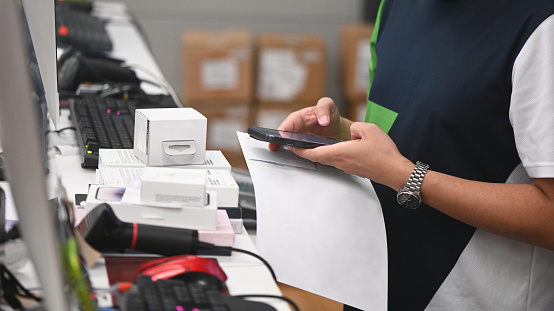 Close-up of seller ordering the goods by mobile phone at check out counter in electronics store