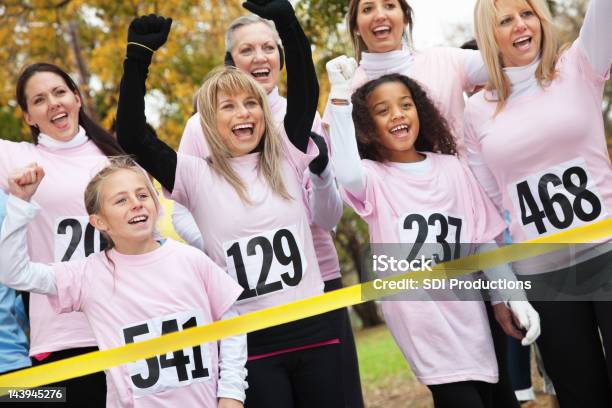 Foto de Equipe De Mulheres Em Rosa Cruzar A Linha De Chegada De Caridade Corrida e mais fotos de stock de Correr