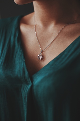 A closeup shot of a female wearing a beautiful silver necklace with a diamond pendant