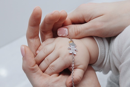 A closeup shot of a female putting a cute bracelet on her baby's hand