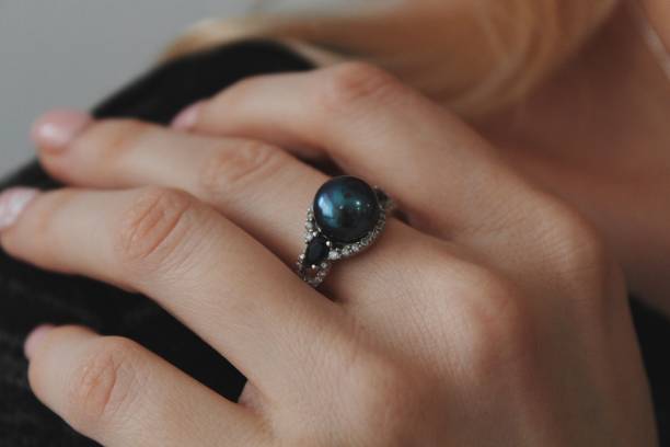 Closeup shot of a female wearing a beautiful ring with a black pearl A closeup shot of a female wearing a beautiful ring with a black pearl earring gold diamond jewelry stock pictures, royalty-free photos & images