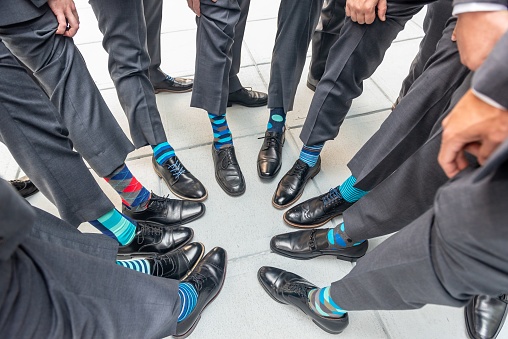 A high angle shot of the groomsmen standing in a circle and showing their colorful socks