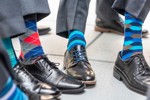 A group of groomsmen wearing colorful socks at a wedding ceremony