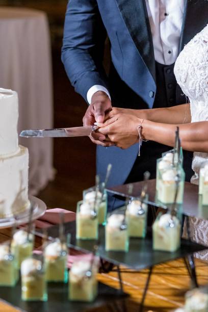 istock Bride and the groom cutting the beautiful white wedding cake 1439457363