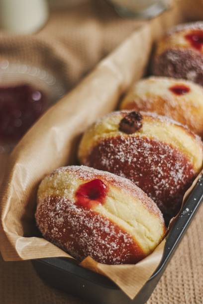 istock Vertical closeup of fluffy doughnuts filled with jam in a container under the lights 1439457695