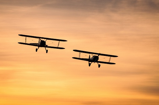 Two biplanes against an orange sunset