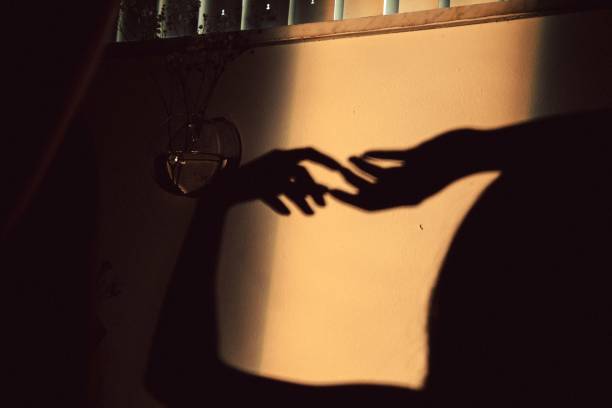 istock Shadow of the two hands touching each other on the wall 1439459382