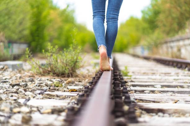 istock Female in jeans walking through the train rails barefoot 1439461312