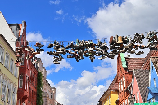 Flensburg, Germany – April 29, 2020: Shoes hanging between old houses in the german northernmost town called Flensburg.