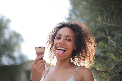A closeup shot of a curly-haired lady with an ice cream in her hands