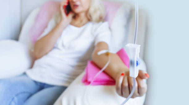 iv drip blur background of Woman making in hospital, talking at mobile phone while needle is in arm alternative therapy stock pictures, royalty-free photos & images