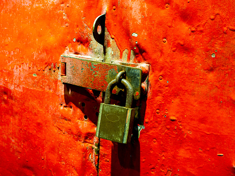 Old master key is lock on red steel door. An old rusted red iron door locked with a master key.