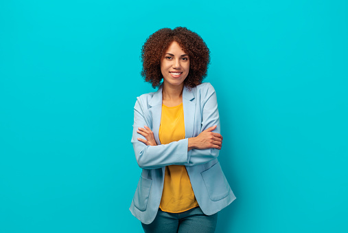 Portrait of a smiling successful African American woman with curly hair in a jacket on a blue background, Hiring, career concept