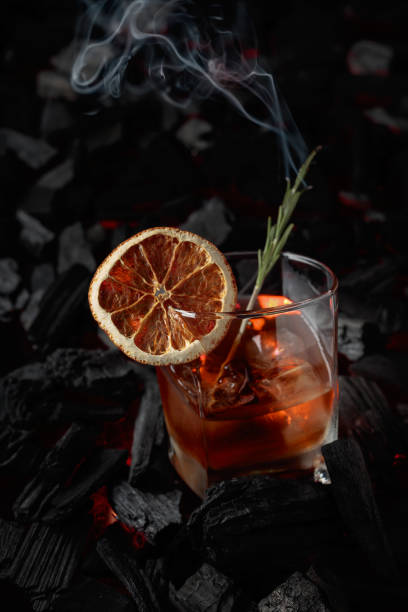 Old-fashioned cocktail with ice, dried orange slice, and rosemary. stock photo