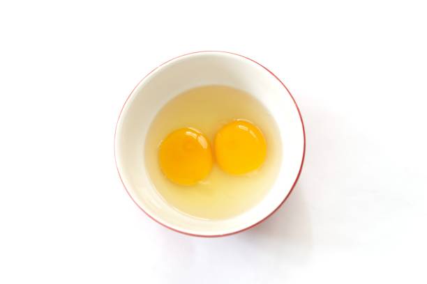 Egg yolks in bowl isolated on white background. Top view two raw egg yolk in bowl.