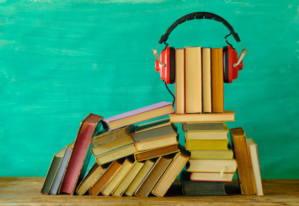audio book concept with stack of books and vintage red headphone on teal background,good copy space. stock photo
