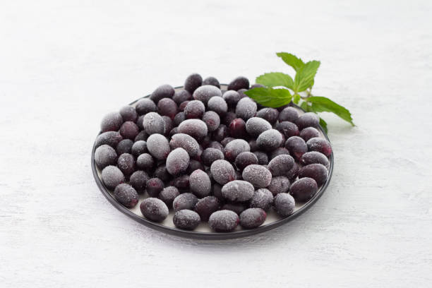 A plate with frozen black grapes on a light gray background. Homemade fruit preparation A plate with frozen black grapes on a light gray background. Homemade fruit preparation frozen grapes stock pictures, royalty-free photos & images