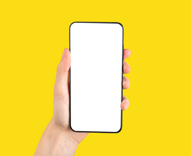 Hand holding phone mockup in vertical position on yellow background. Smartphone template with blank screen for mobile application, social networking site ad.
