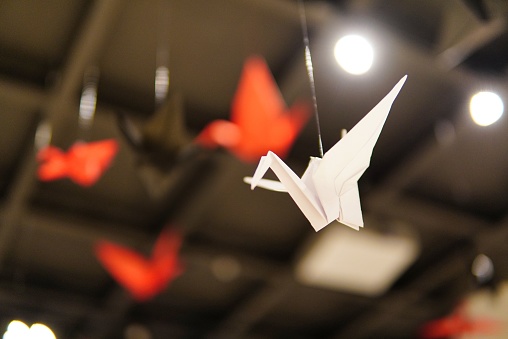 A low angle closeup shot of origami made colorful paper bird flying over