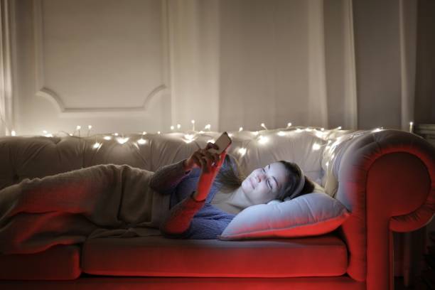 istock Woman playing with her phone lying down on the sofa at night 1439492726