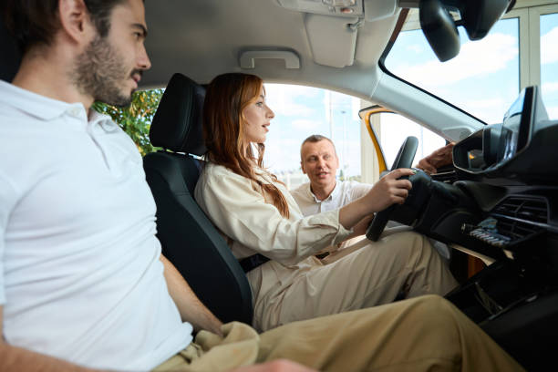 istock Car salesperson showing instrument panel to his customers 1439493208