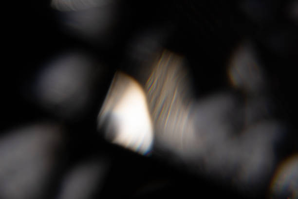 黒い背景に青い光フレアプリズムレインボーフレアオーバーレイ効果、クリスタルを横切る光、プリズムサンキャッチャー反射光線。暗い背景に抽象的なぼかしたカラフルなレンズフレアボ� - lighting technique aperture lens color image ストックフォトと画像