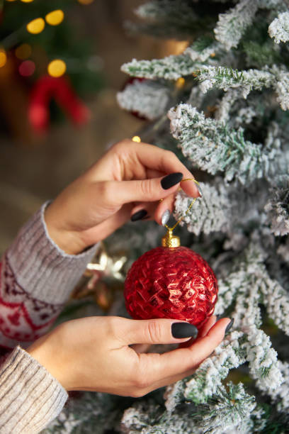 istock woman hand hangs toy ball on Christmas tree 1439494936
