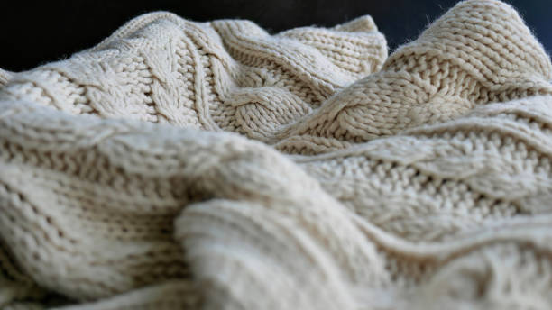 istock Selective focus Knitted Woolen, Knitwear Fabric Texture, Warm Clothes for Fall and Winter, Woven, Woolen, Sweaters, beige, cream color with Dark Background and copy space 1439498532