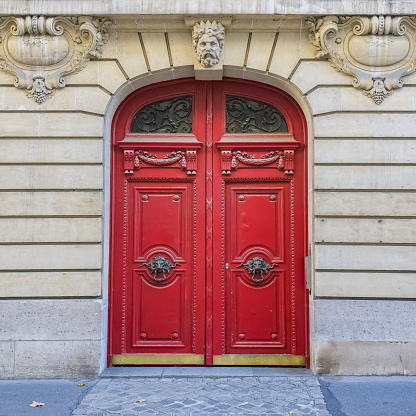 Paris, an ancient red wooden door, beautiful facade in a luxury neighborhood, in the 8e arrondissement