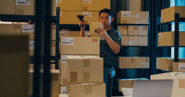 istock Asian businessman use barcode scanner scan paper box in shelf and put data in digital tablet cut stock online data information detail for express delivery at warehouse. 1439502509