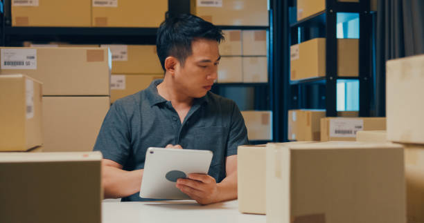 istock Asian businessman with barcode machine and box use digital tablet checking stock on shelf and key data in online information detail in before express delivery at warehouse. 1439502542