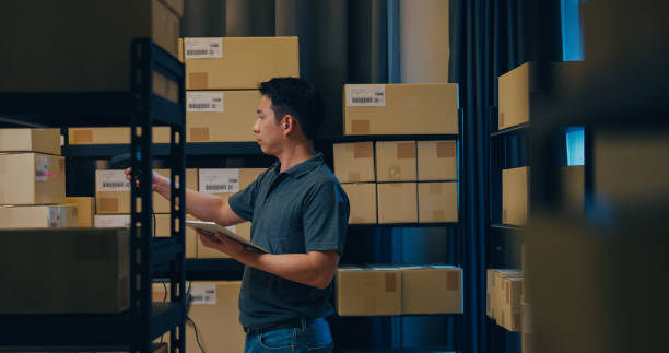 istock Asian businessman use barcode scanner scan paper box in shelf and put data in digital tablet cut stock online data information detail for express delivery at warehouse. 1439502607
