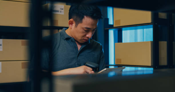 istock Asian businessman use barcode scanner scan paper box in shelf and put data in digital tablet cut stock online data information detail for express delivery at warehouse. 1439502610