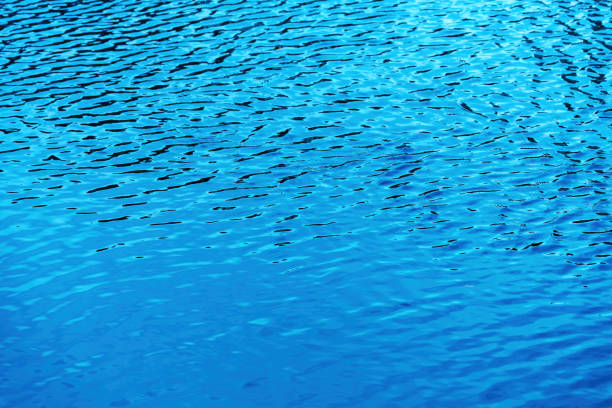 Natural background of water in summer. Blue surface. Clear water with ripples and splashes. water waves in sunlight The water surface has waves.
