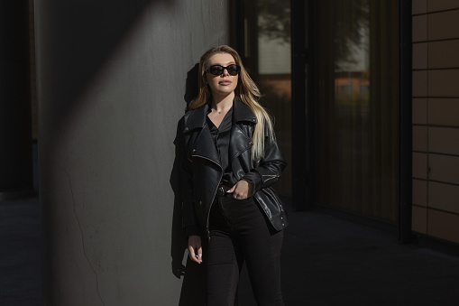 Young woman in black clothing outdoor over black city background wearing sunglasses