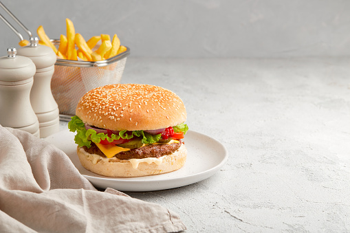 Fresh tasty burger, french fries and ketchup on gray background. Fastfood restaurant menu