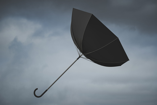 Caught in a gust of wind, an umbrella turned inside out in flight. Stormy overcast weather