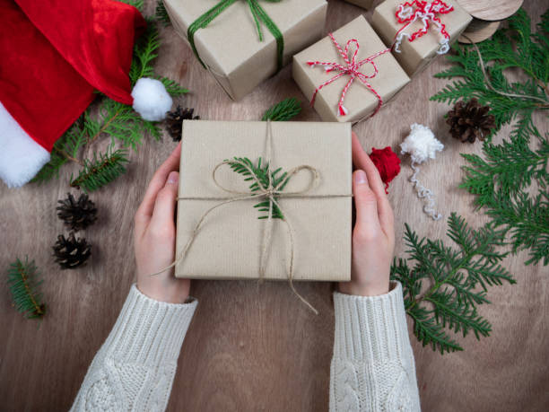 Eco friendly gift. Sustainable gift wrapping. Plastic-free packaging. Hand holds a gift box. Wrap Christmas gifts with recycled paper and linen or wool thread. stock photo