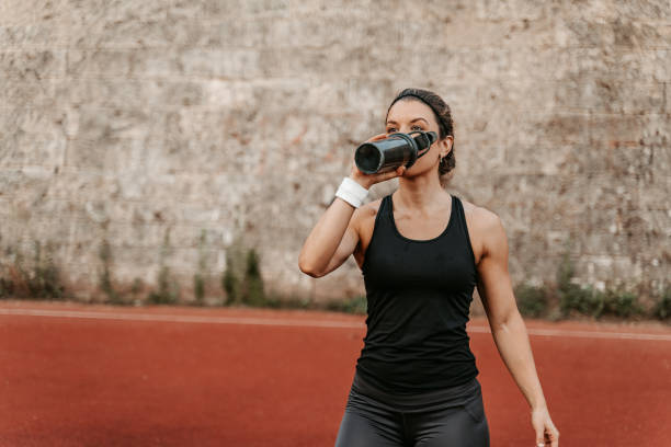 istock Young Woman Drinking Water On A Running Track 1439517313