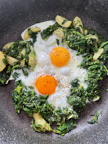 close up of fried eggs with spinach and potatoes