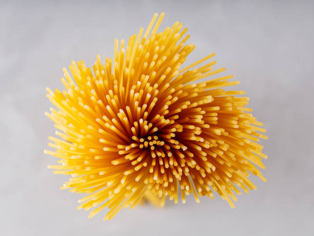 istock Spaghetti shaped like a flower. Raw spaghetti pasta on gray background. Top view 1439521674