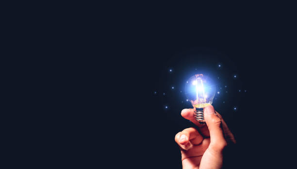 istock Hand holding light bulb glowing with connection line for creative thinking ideas and innovation concept. Renewable energy concept for sustainable, resource and environment icons on black background. 1439528279