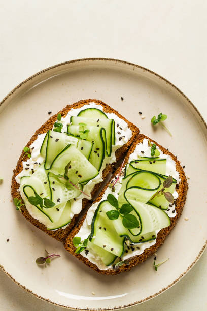istock Breakfast, cereal bread sandwiches, cream cheese, sliced cucumber, with micro greenery on a light table, close-up, top view, selective focus, no people, 1439529867