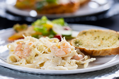 Tasty shrimp fettuccine alfredo with parmesan on light blue background