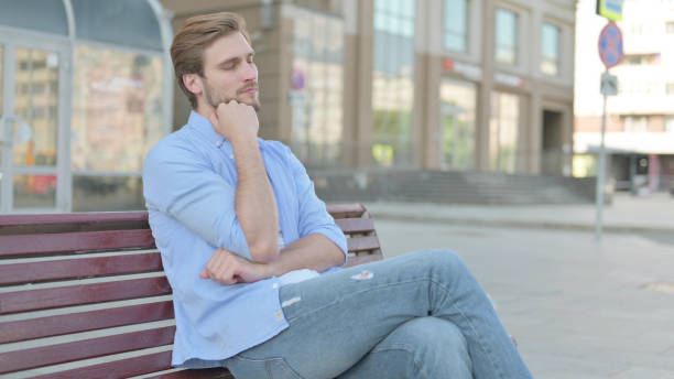 istock Tired Man Sleeping while Sitting Outdoor on Bench 1439530413
