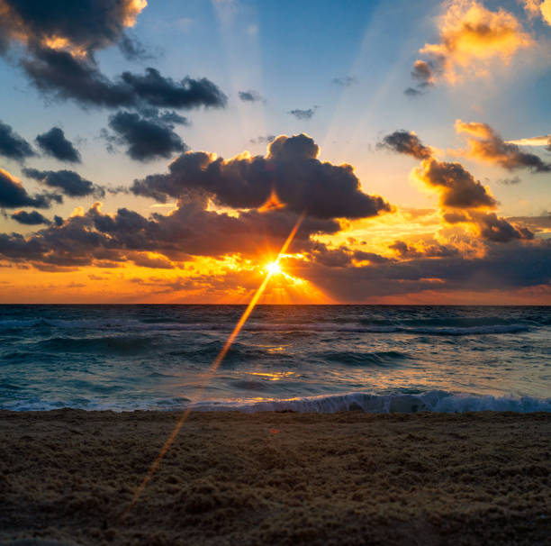 Sunrays coming through Clouds at Sunrise over Water