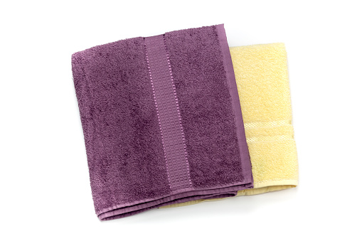 Two new towels yellow and purple colors on white background close-up