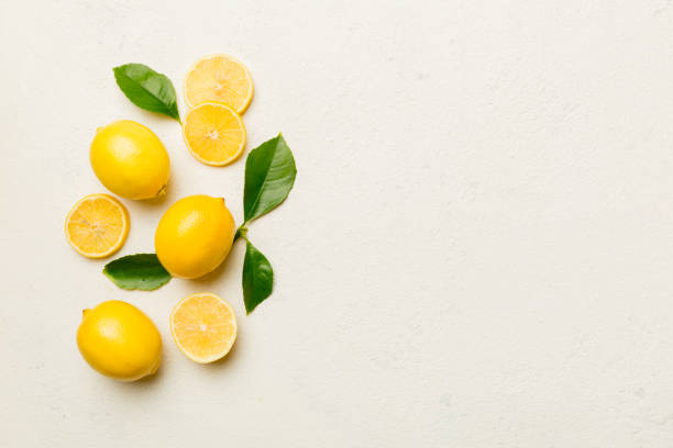 istock Many fresh ripe lemons with green leaves on colored background, top view, space for text 1439537698