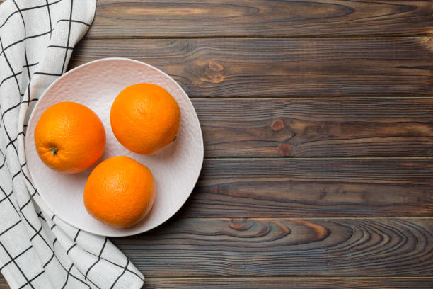 istock Flat lay of Fresh orange fruit with sliced in plate on Colored background. Top view with copy space 1439537702